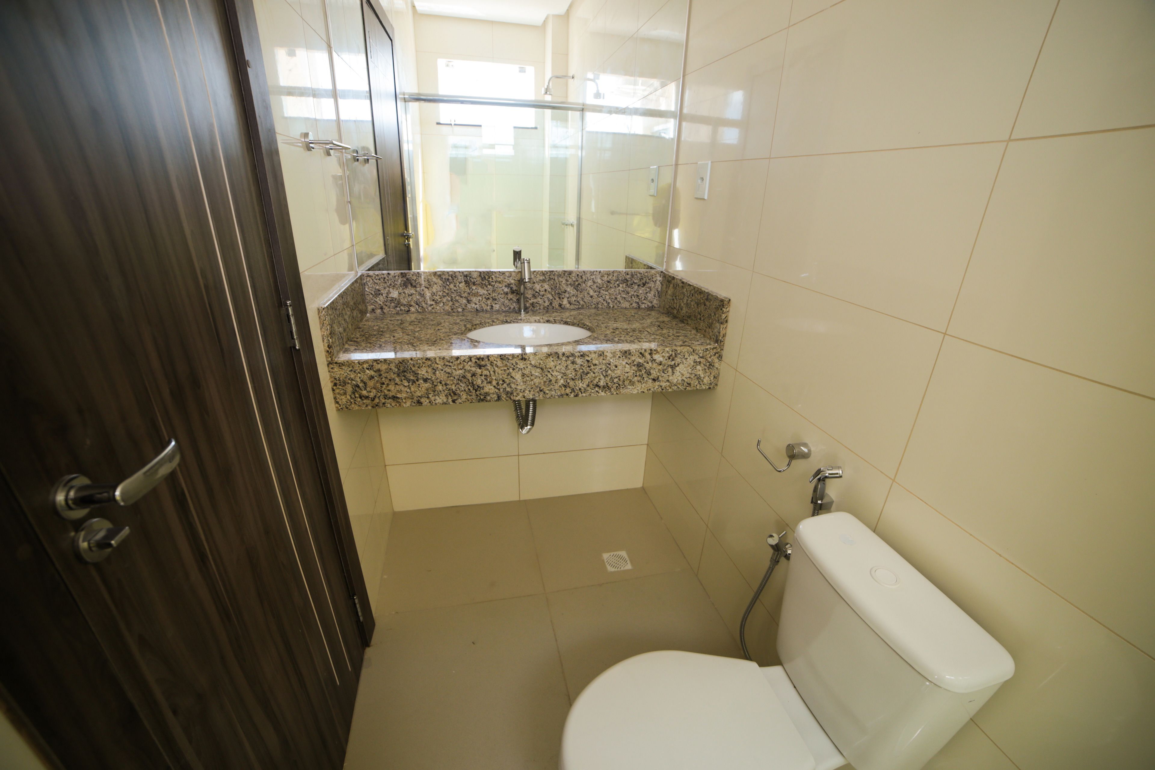 A bathroom with a granite countertop sink, a toilet, and a shower area.