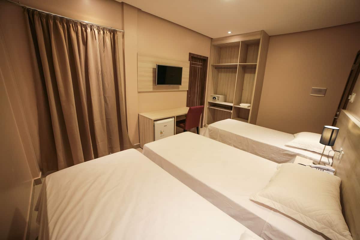 A hotel room with two beds, a desk, a TV, and a wardrobe.