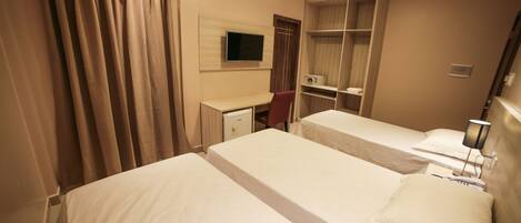 A hotel room with two beds, a desk, a TV, and a wardrobe.