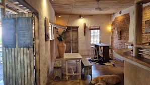 Een rustiek interieur met een houten tafel, krukken, een grote vaas, en een slapende hond.