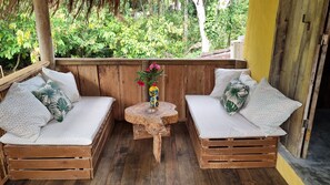 A wooden bench seating area with a small table and a vase of flowers. - Casa Namoa Pousada (Cairu)