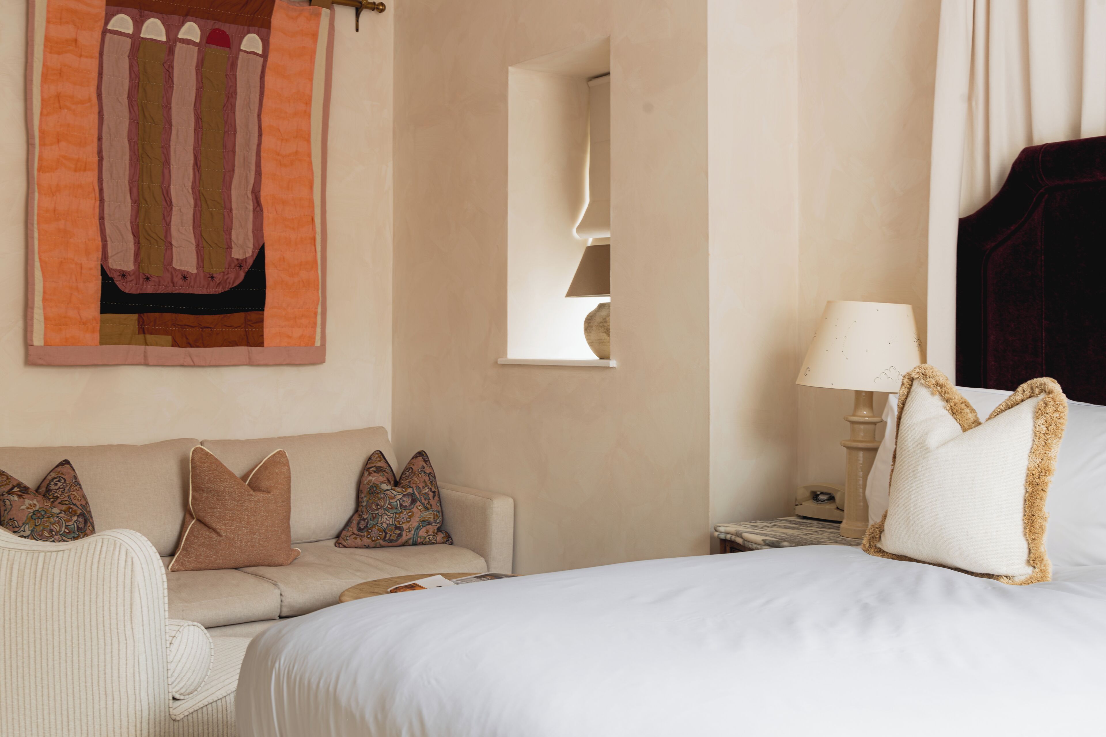 Ein Hotelzimmer mit einem Bett, einer Couch, einer Lampe und einem an der Wand befestigten Kunstwerk.