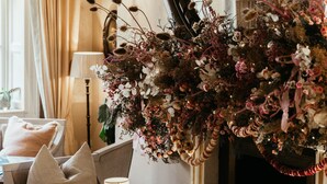 A room with a dining table set for two, a large mirror, and a vase of flowers.