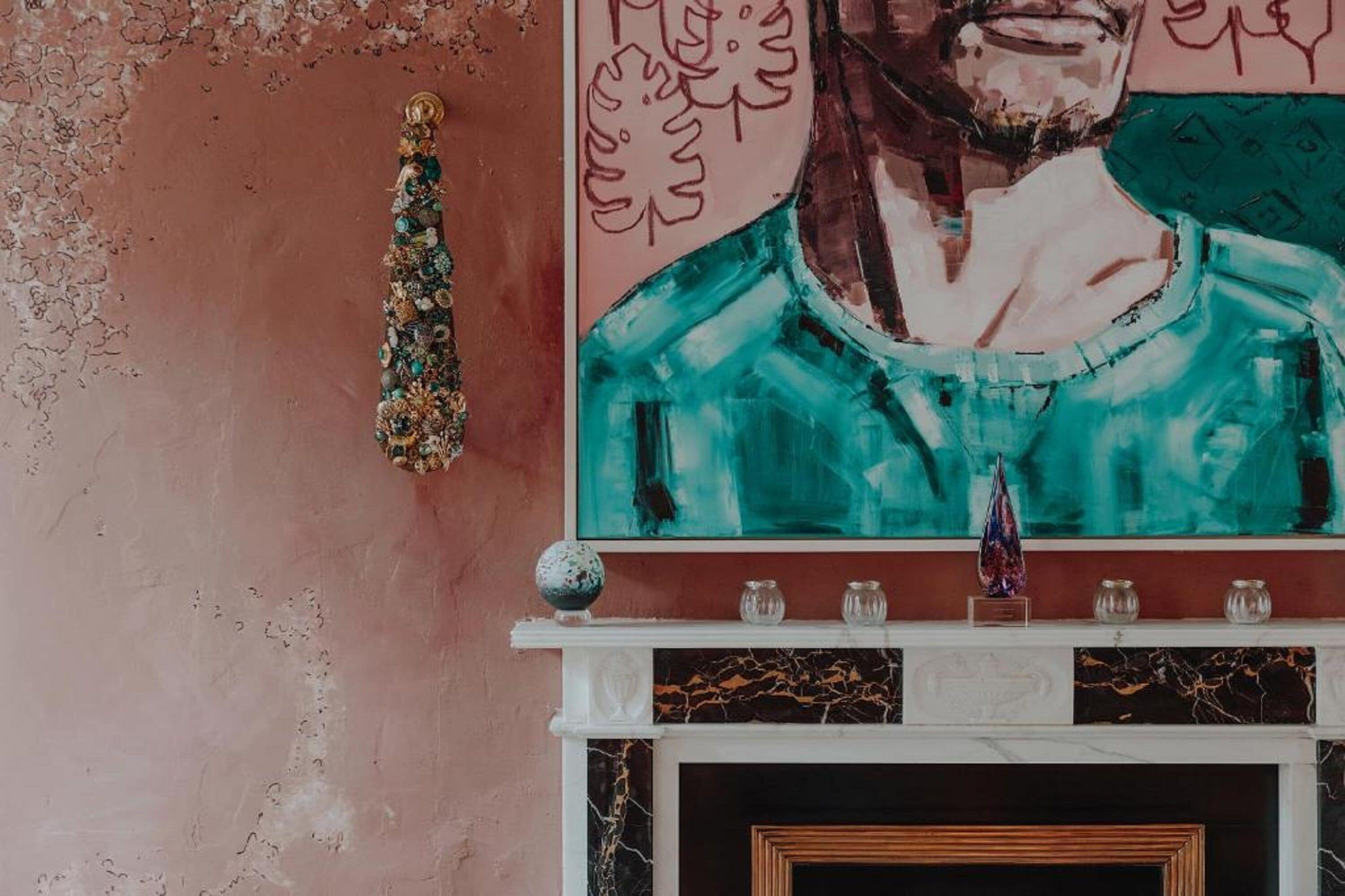 A fireplace with a marble mantle, a decorative wall hanging, and a framed artwork above it.