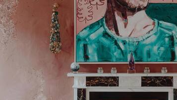 A fireplace with a marble mantle, a decorative wall hanging, and a framed artwork above it.
