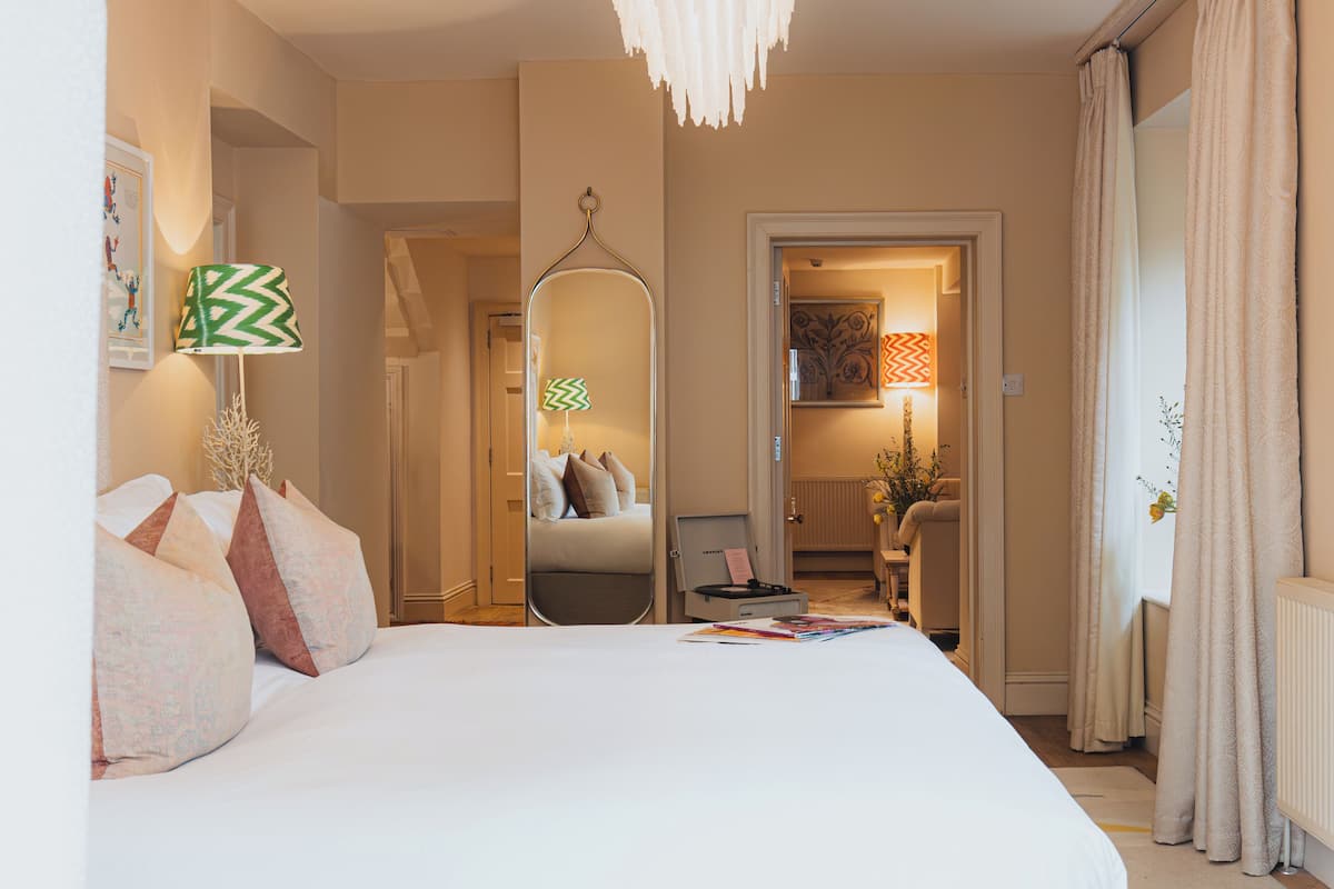 A hotel room with a large bed, a mirror, a desk, and a chair.