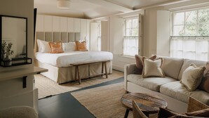 A spacious bedroom with a large bed, a sofa, and a dining area.