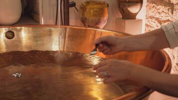 A person using a tool on a large copper basin.
