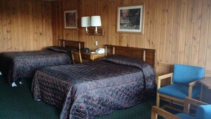 A room with two beds, a chair, a nightstand, and a wall-mounted lamp. - Marlinton Motor Inn (Marlinton)