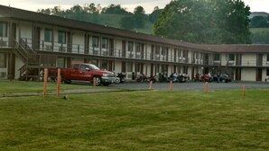 A motel with a covered parking area and a red truck parked in front. - Marlinton Motor Inn (Marlinton)