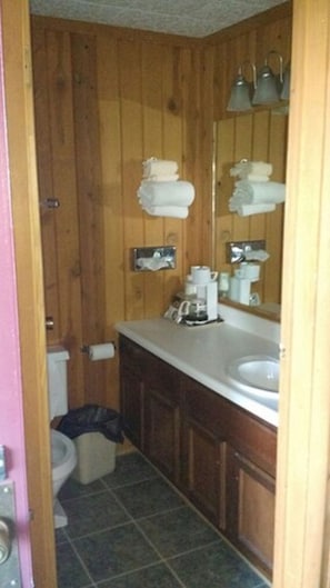 Bathroom with toilet, sink, and coffee maker.