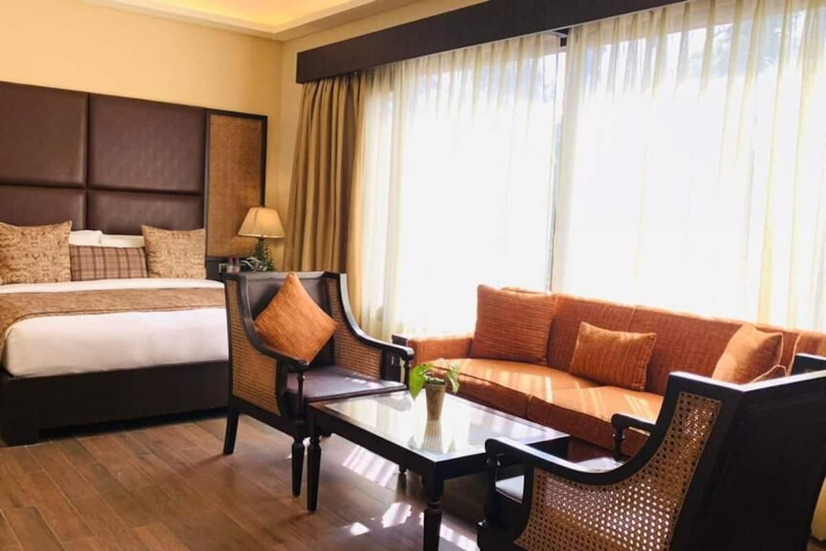 A hotel room with a bed, a sofa, a coffee table, and a nightstand with lamps.