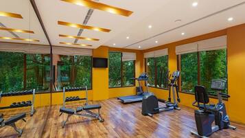 A gym with exercise equipment, large windows, and a wooden floor.
