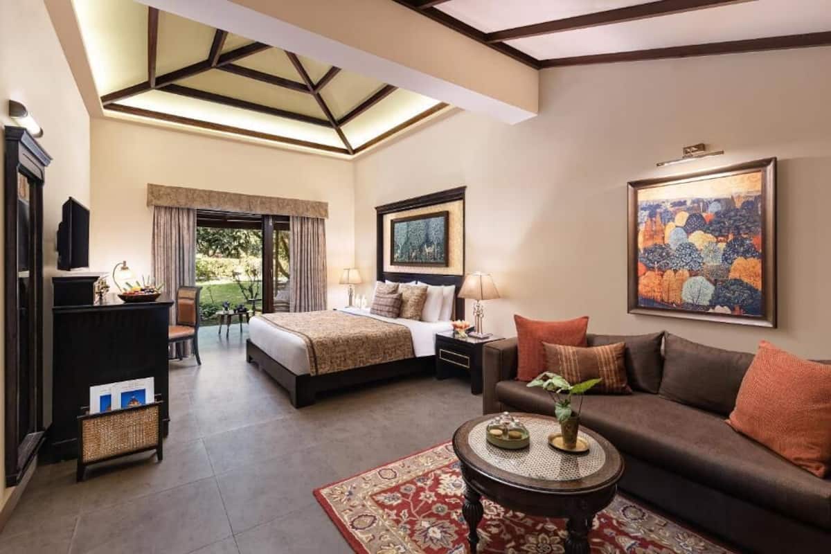 Habitación de hotel con cama, sofá, mesa de centro, televisor y obras de arte en las paredes.