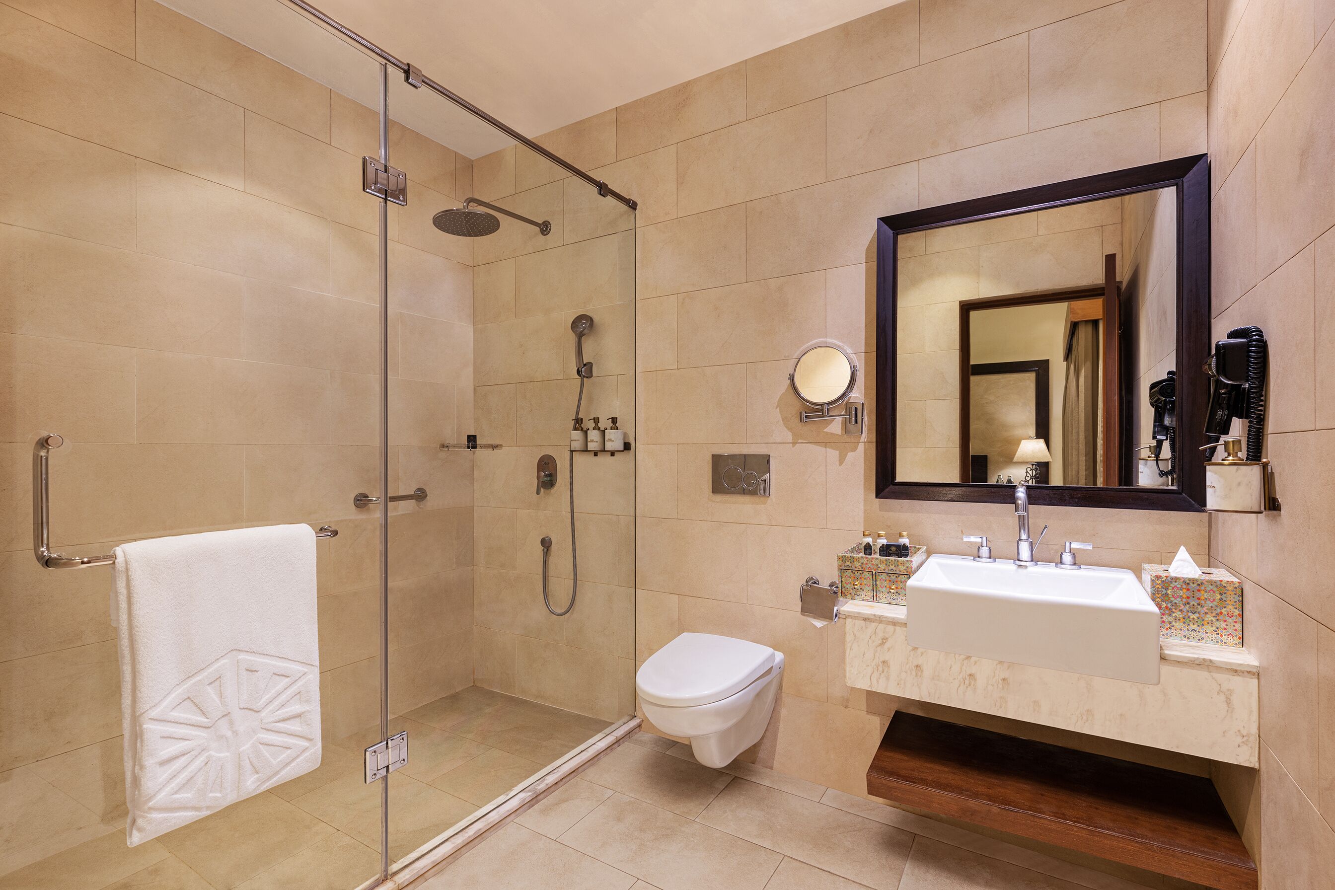 Une salle de bain moderne avec une douche à parois de verre, des toilettes blanches et un meuble-lavabo avec un évier et un miroir.