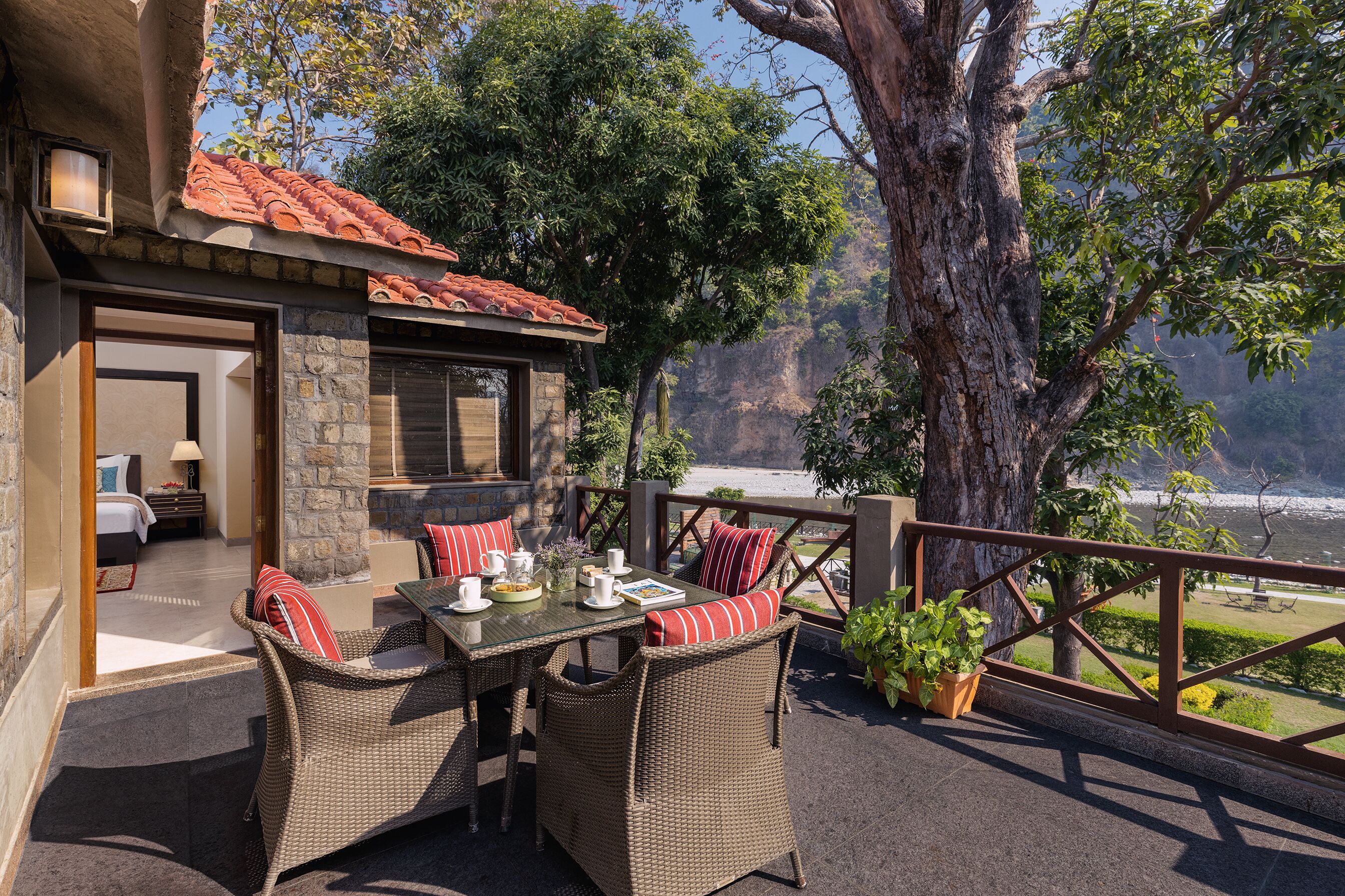 A patio with wicker furniture, a table set with cups and a book, and a view of the ocean.