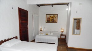 Un dormitorio con dos camas, una puerta de madera, un cuadro y un espejo en la pared.
