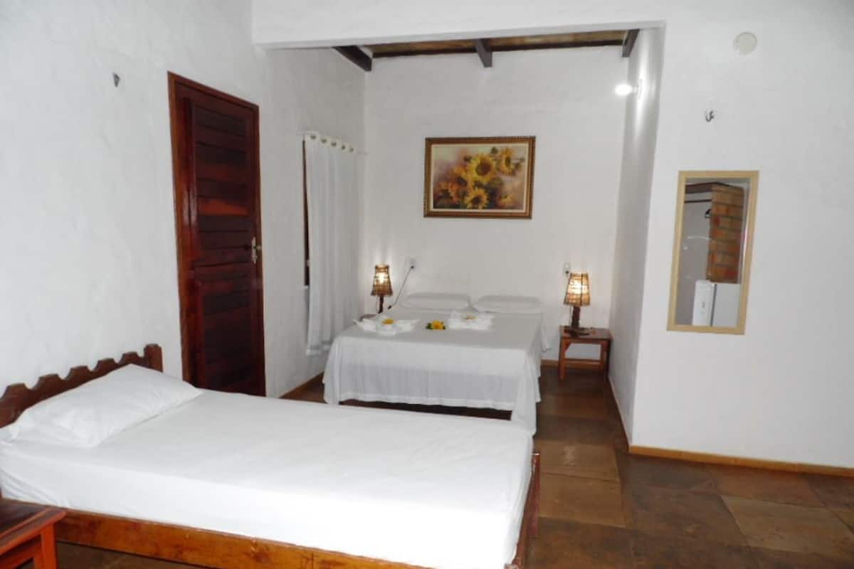Un dormitorio con dos camas, una puerta de madera, un cuadro y un espejo en la pared.