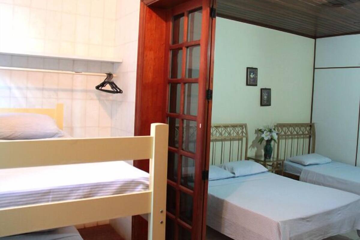 A dormitory room with two single beds, a wooden door, and a small table with a vase.
