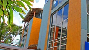 A modern building with large windows and a mix of blue and orange exterior walls. - Pousada Praia da Costa (Vila Velha)
