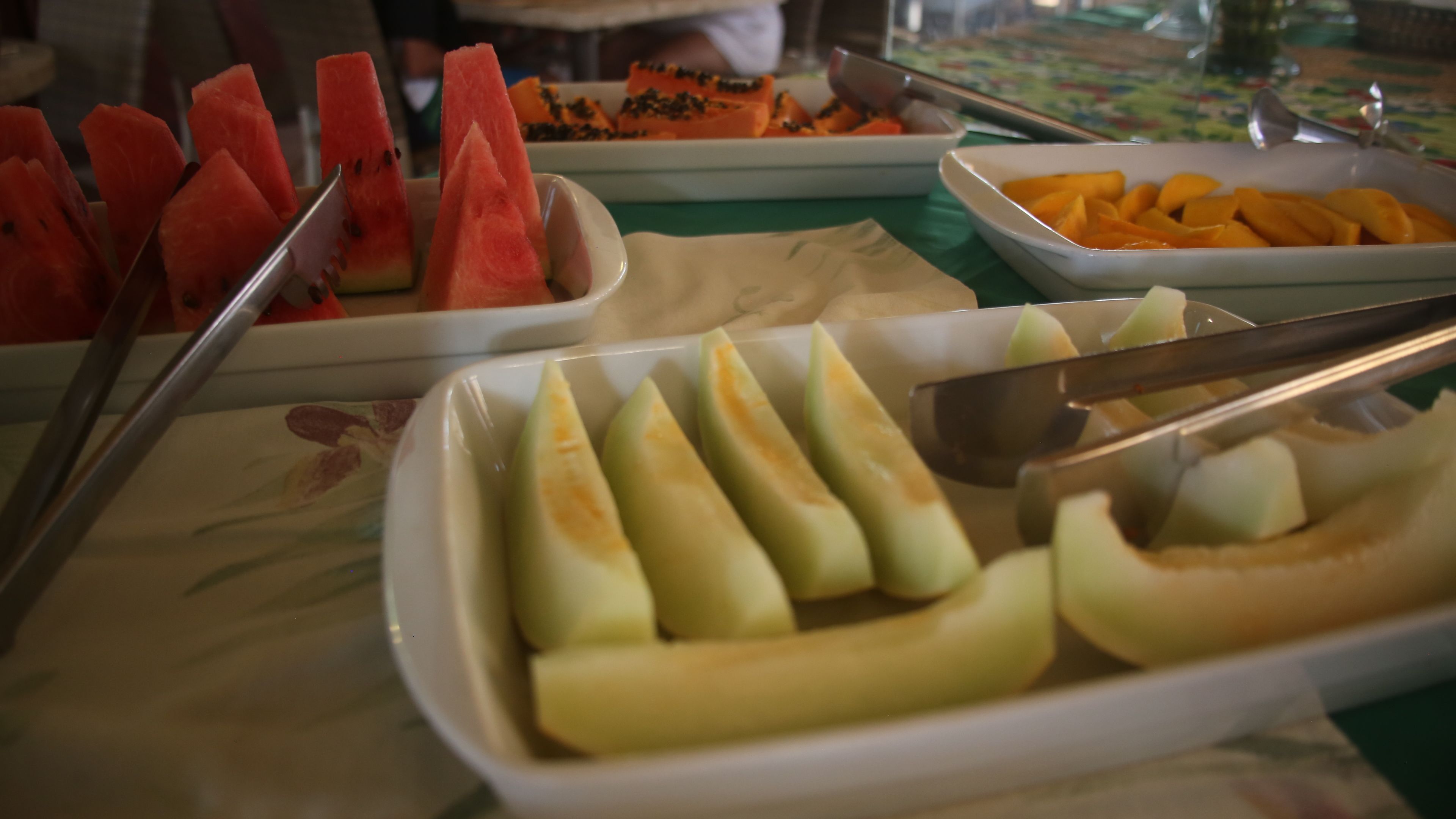 A buffet with various fruits and vegetables, including watermelon, mango, and green apples.