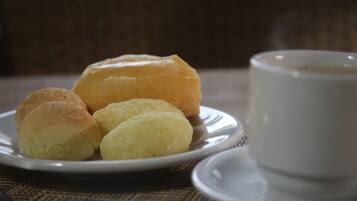 A plate with three pastries and a cup of coffee on a table.