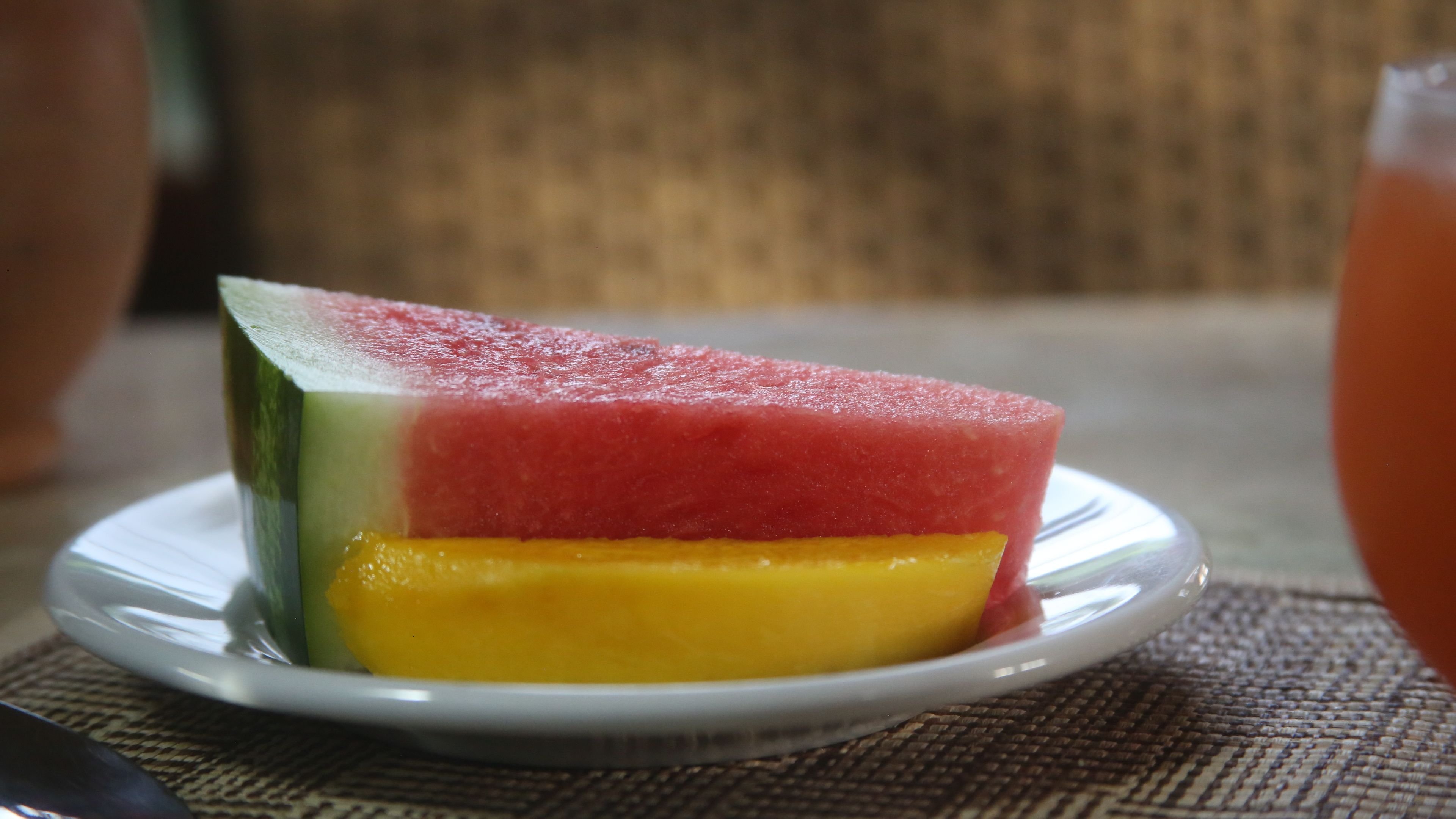A slice of watermelon and mango on a white plate.