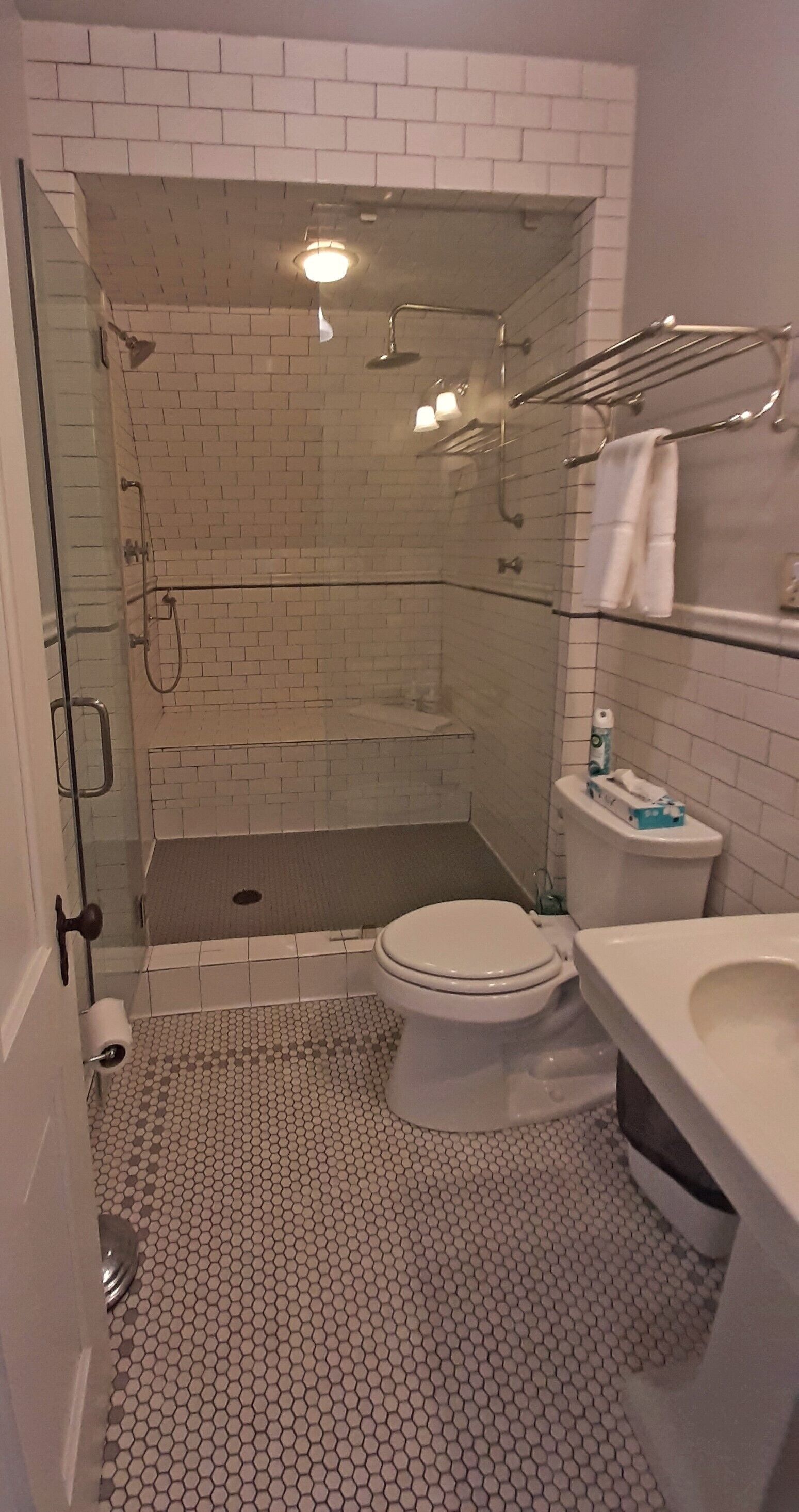A bathroom with a glass-enclosed shower, a toilet, and a sink.