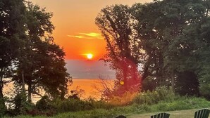 A sunset view with chairs facing a lake, surrounded by trees. - Four Mounds Inn (Dubuque)