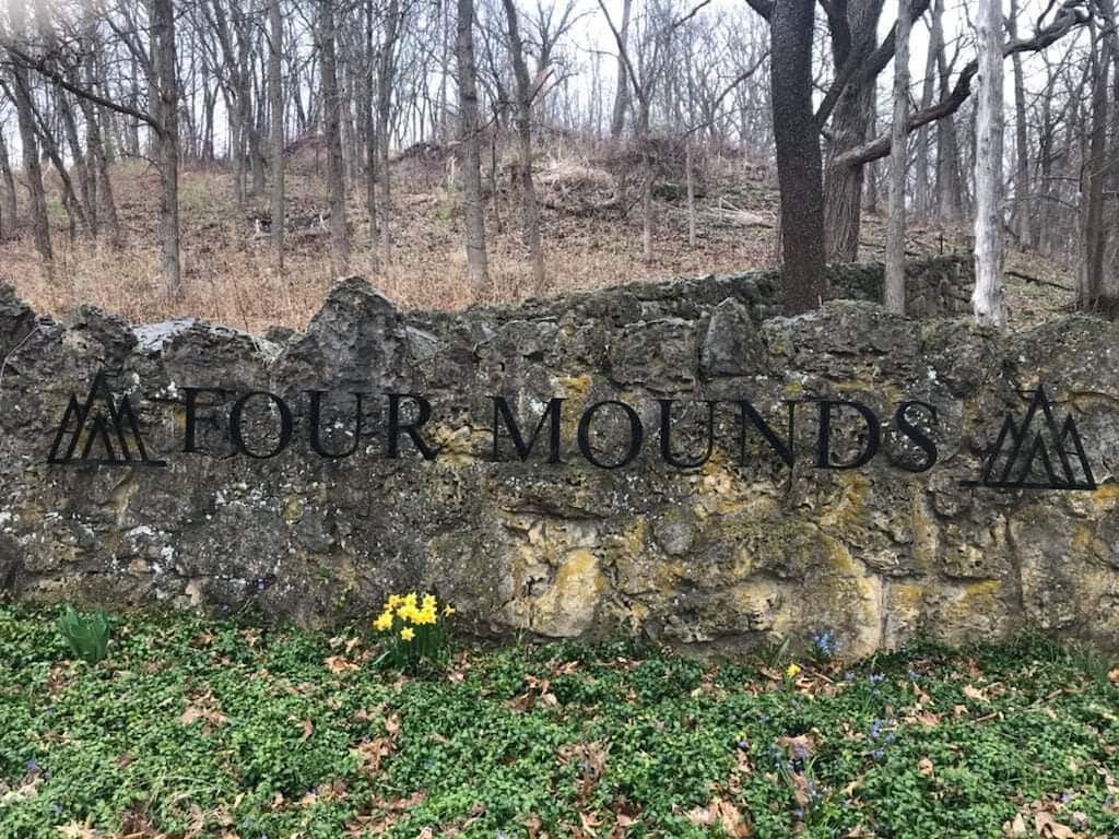 Un muro de piedra con la inscripción “FOUR MOUNDS” grabada.
