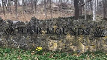 Un muro de piedra con la inscripción “FOUR MOUNDS” grabada.