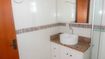 A bathroom with a white sink, a mirror, a towel rack, and a wooden door.