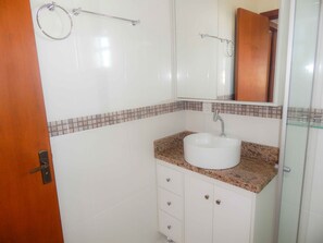 A bathroom with a white sink, a mirror, a towel rack, and a wooden door. - Apartamento Gran Estilo 01 (Canela)