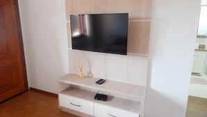 Una sala moderna con un televisor de pantalla plana montado en un mueble de madera, una mesita con un control remoto y un cajón debajo.