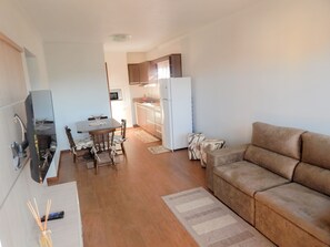 A compact living space with a kitchenette, a dining area, and a seating area. - Apartamento Gran Estilo 01 (Canela)