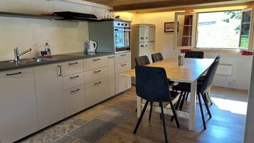 Una cocina moderna con comedor, techo de madera y ventana con cortinas.