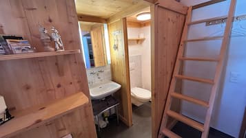 A wooden interior with a bathroom, including a sink, toilet, and a wooden ladder.