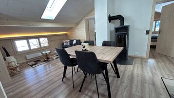 A modern loft-style living space with a dining area, a fireplace, and a large skylight.