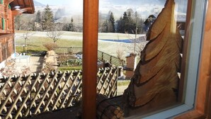 A wooden cabin with a view of a snowy landscape and a wooden sculpture.
