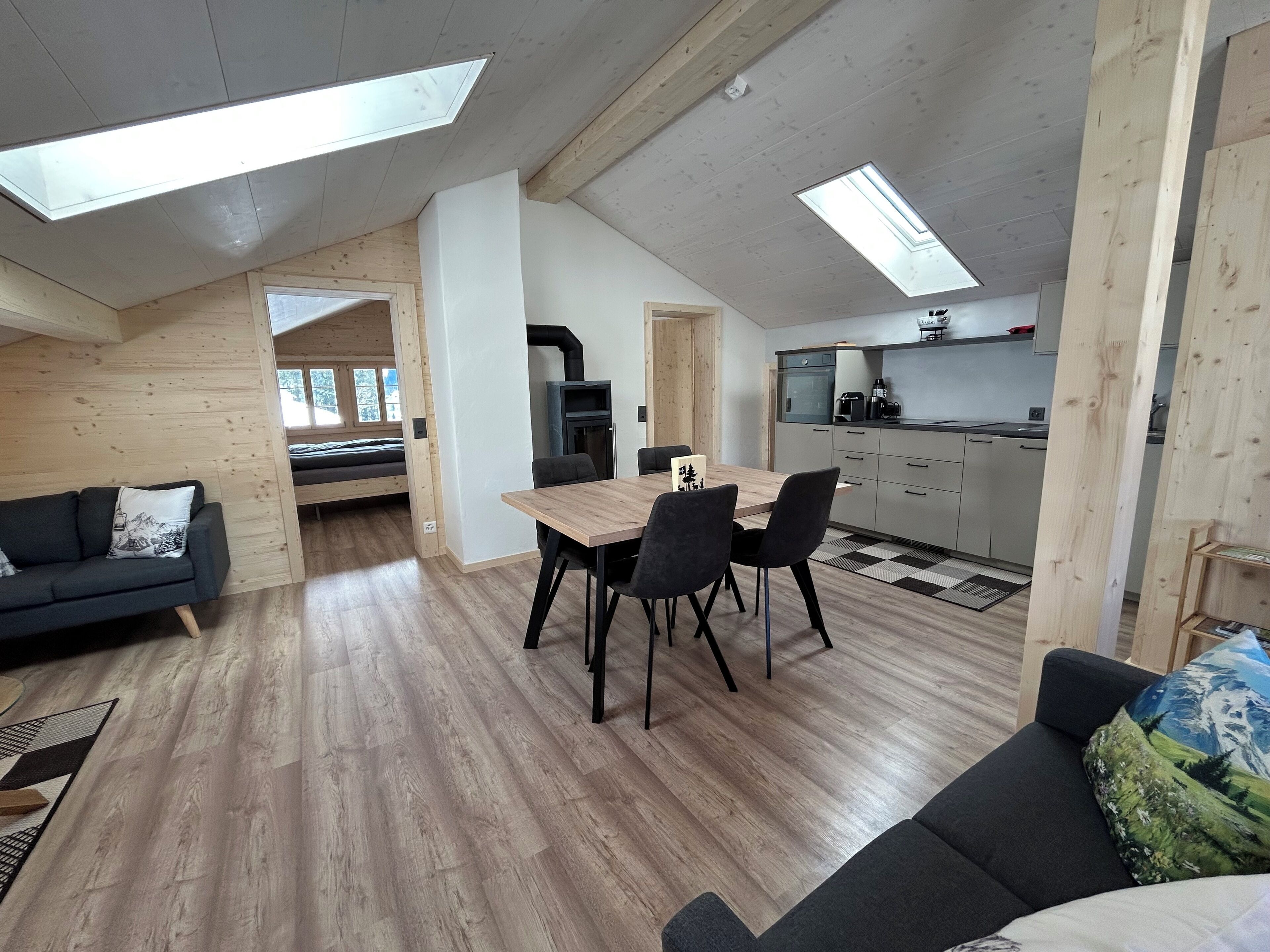 A modern loft-style apartment with a dining area, kitchen, and a loft bedroom.