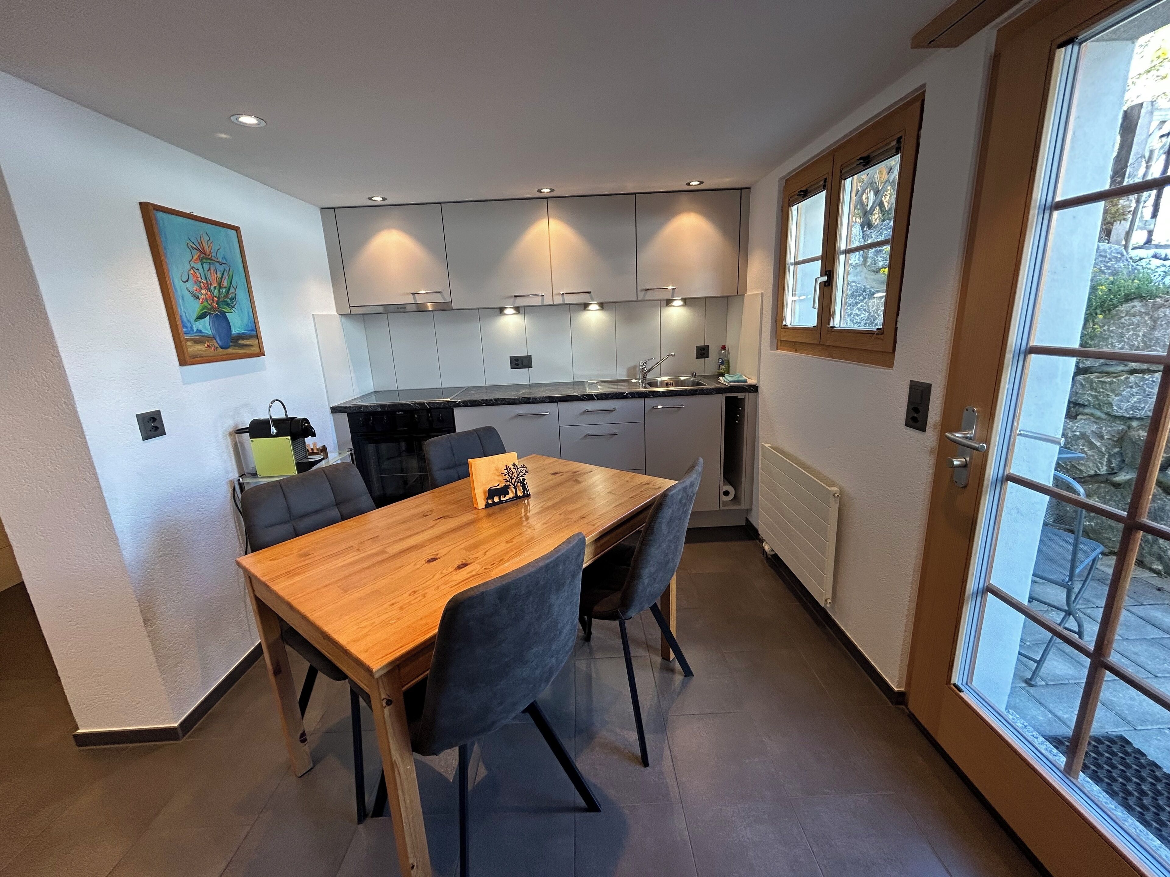 Una cocina moderna con una mesa de comedor de madera, sillas grises y una ventana con vistas al exterior.