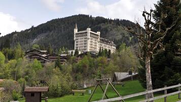 A large hotel with multiple buildings, a wooden swing set, and a fenced area with picnic tables.