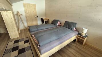Una camera da letto con un letto in legno, una scrivania, una sedia e un comodino con una lampada.