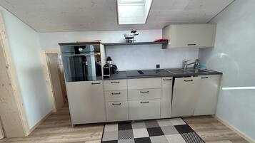 A compact kitchen with a built-in coffee machine, a sink, and a window above the countertop.