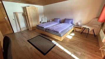 Une chambre à coucher avec un lit en bois, une armoire, une chaise et une petite table.