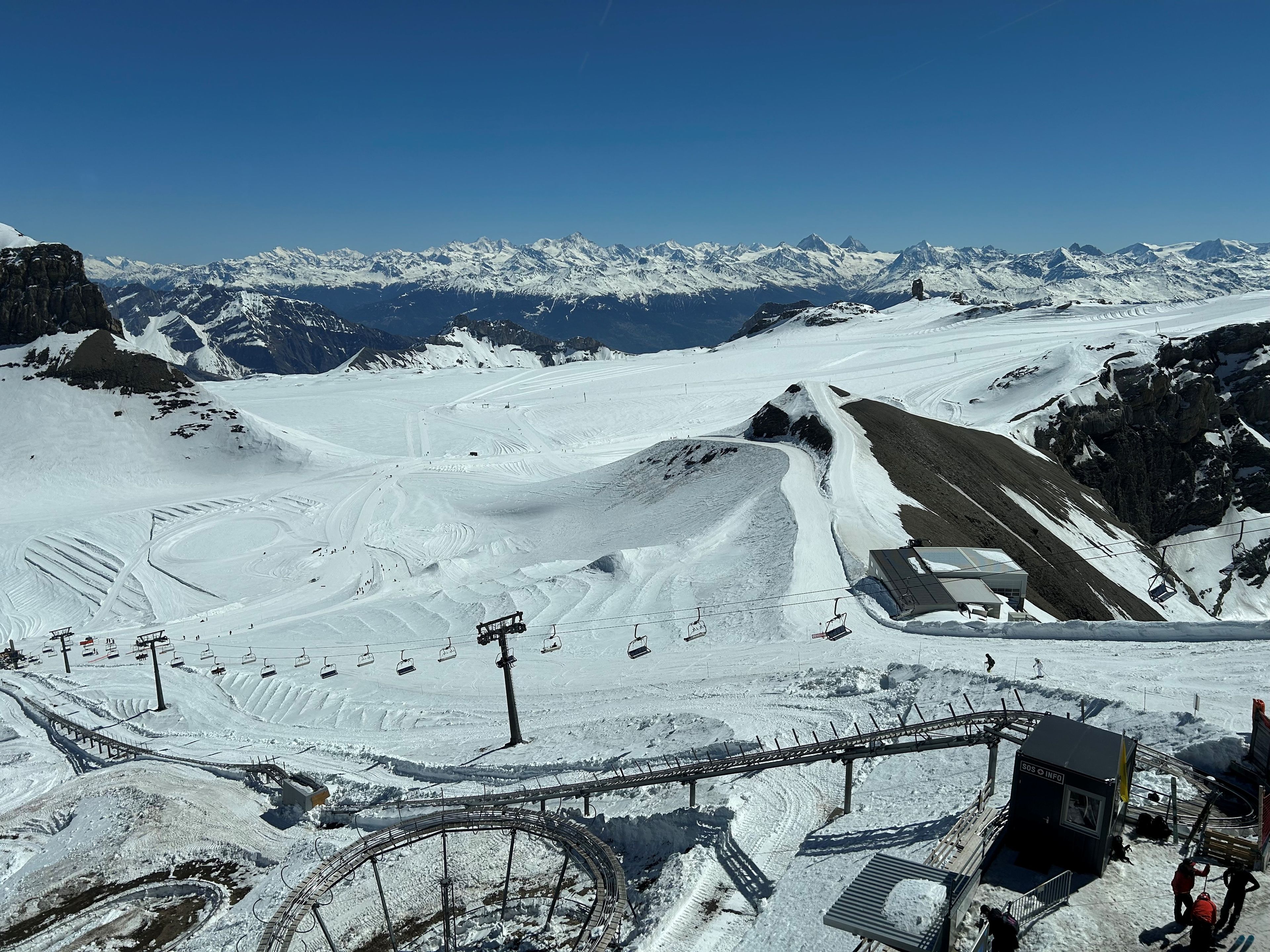 A snow-covered ski resort with ski lifts, a chairlift, and a mountain backdrop.