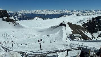 A snow-covered ski resort with ski lifts, a chairlift, and a mountain backdrop.