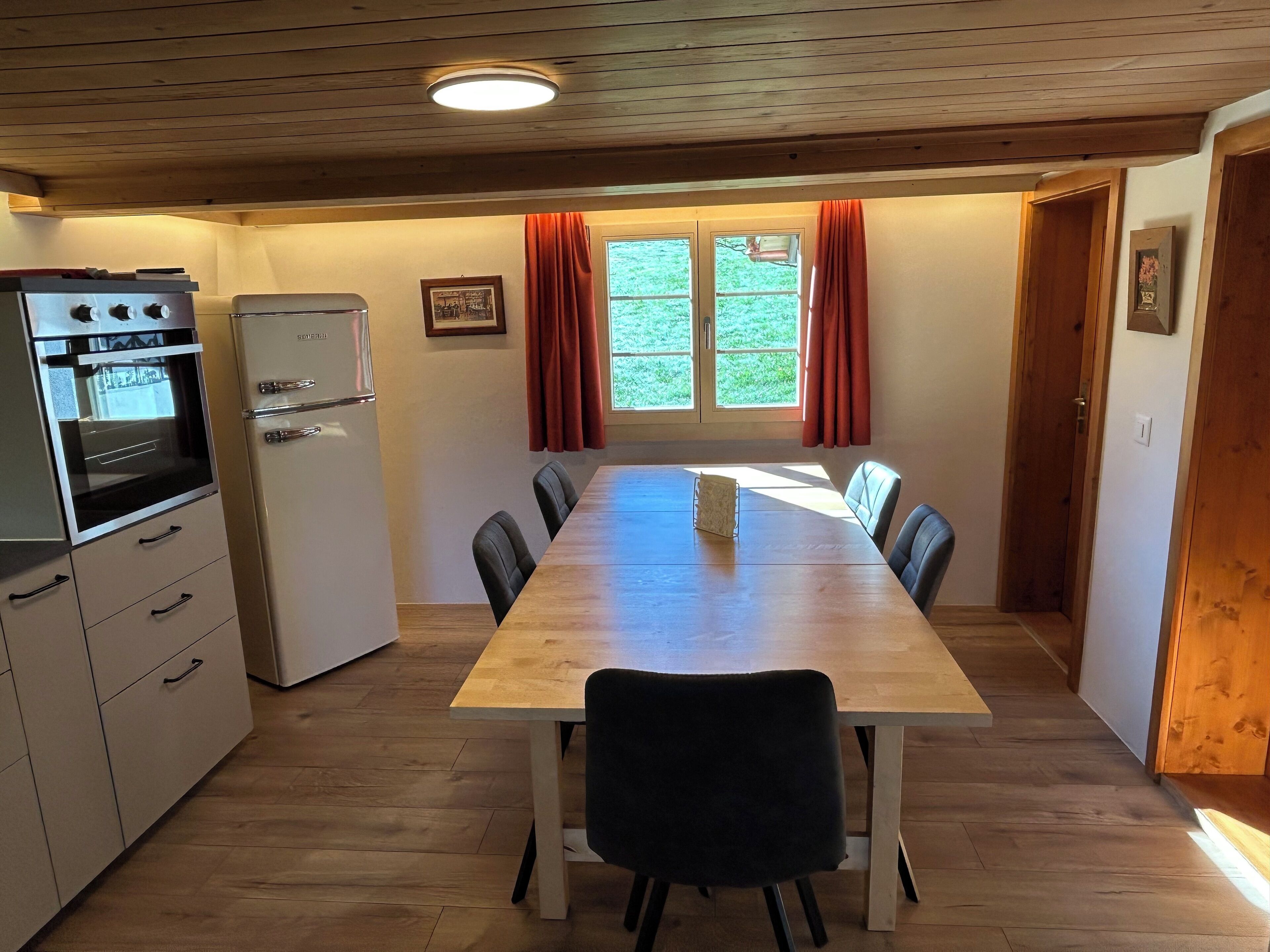 Eine kleine Küche mit Esstisch, Stühlen und einem Kühlschrank.