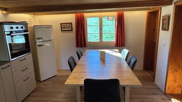 Eine kleine Küche mit Esstisch, Stühlen und einem Kühlschrank.