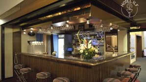 A bar area with a wooden counter, bar stools, and a flower arrangement. - ILF Hotel Prague (Prague)